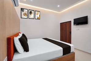 Ein Hotelzimmer mit einem Bett, einem an der Wand montierten Fernseher und einer Tür.