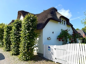 Ein traditionelles Haus mit einem Strohdach, einem weißen Zaun und einem Schild mit der Nummer 12.