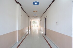 Un pasillo largo y estrecho con piso de baldosas, puertas a ambos lados e iluminación empotrada en el techo.