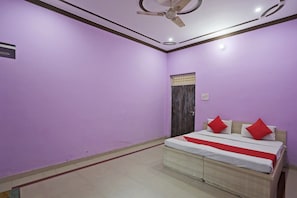 Quarto com cama, ventilador de teto e janela com porta de madeira.