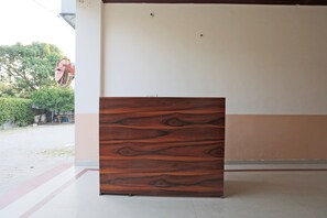 A wooden panel with a natural wood grain pattern, positioned against a wall with a white and brown color scheme. - Hotel O by OYO Surprise Farm House (Aligarh)