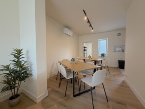 A modern dining area with a wooden table and white chairs, a potted plant, and a ceiling fan. - Stylish stay near the harbor and beach (Blankenberge)