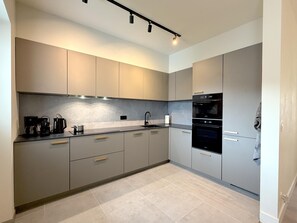 A modern kitchen with grey cabinets, a black countertop, and a built-in oven. - Stylish stay near the harbor and beach (Blankenberge)