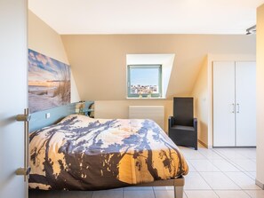 Una camera da letto con un letto, una finestra, una sedia e un armadio.
