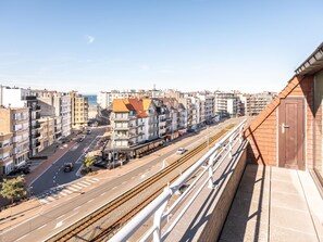 Un grattacielo con un balcone affacciato su una strada trafficata e dei binari ferroviari.