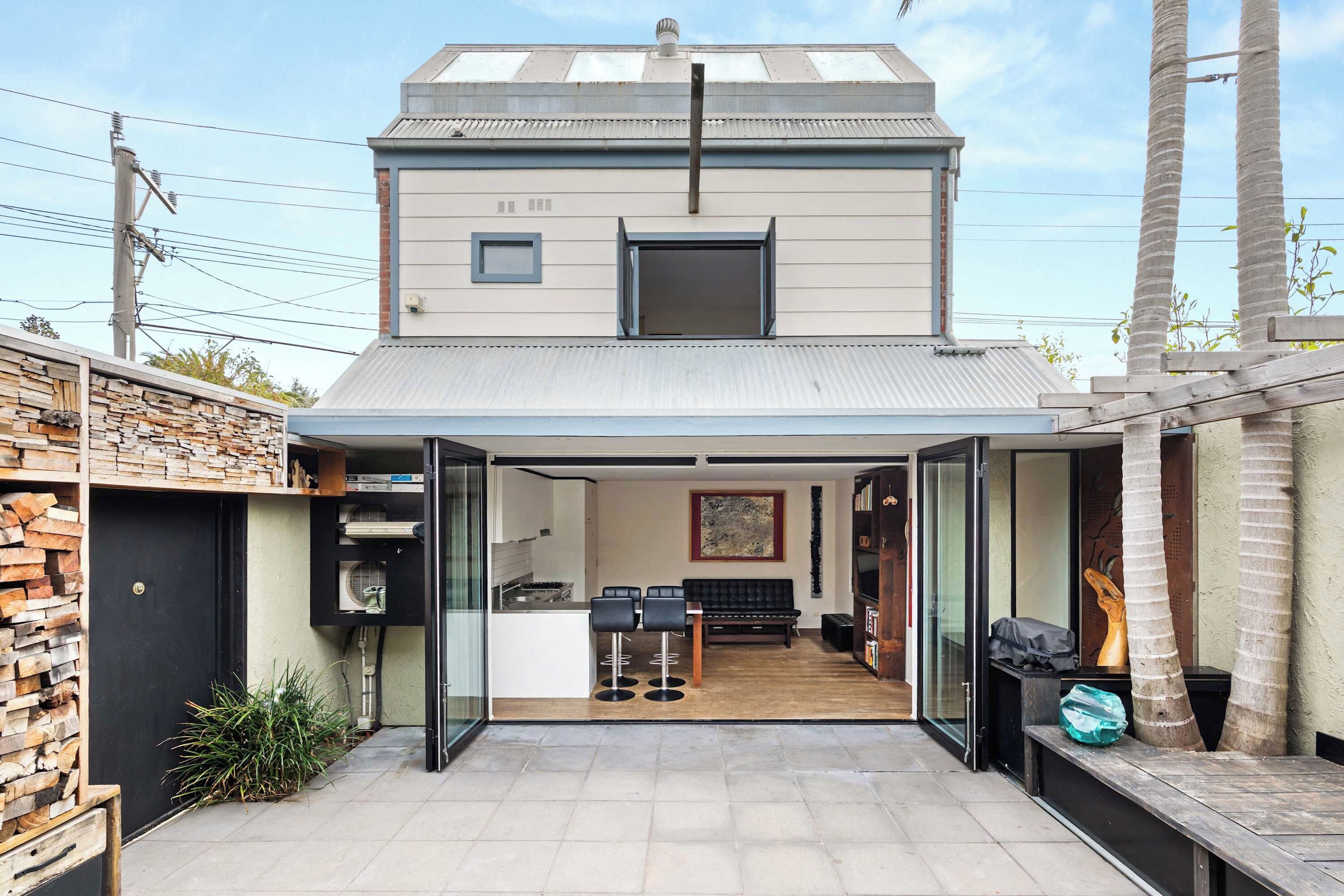 A modern two-story house with a covered patio, a kitchen, and a dining area.
