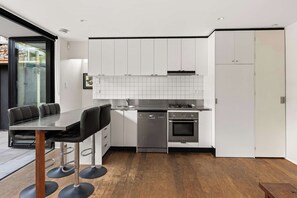 A modern kitchen with a dining area, stainless steel appliances, and a wooden floor. - The Curious Nook - Balaclava Stay (Balaclava)