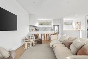A modern living room with a sofa, a coffee table, and a TV mounted on the wall. - Scenic Rise Beach House at the Bay (Apollo Bay)