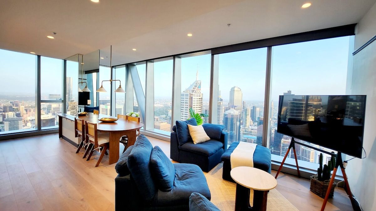 A modern living room with a city view, a dining area, and a flat-screen TV.