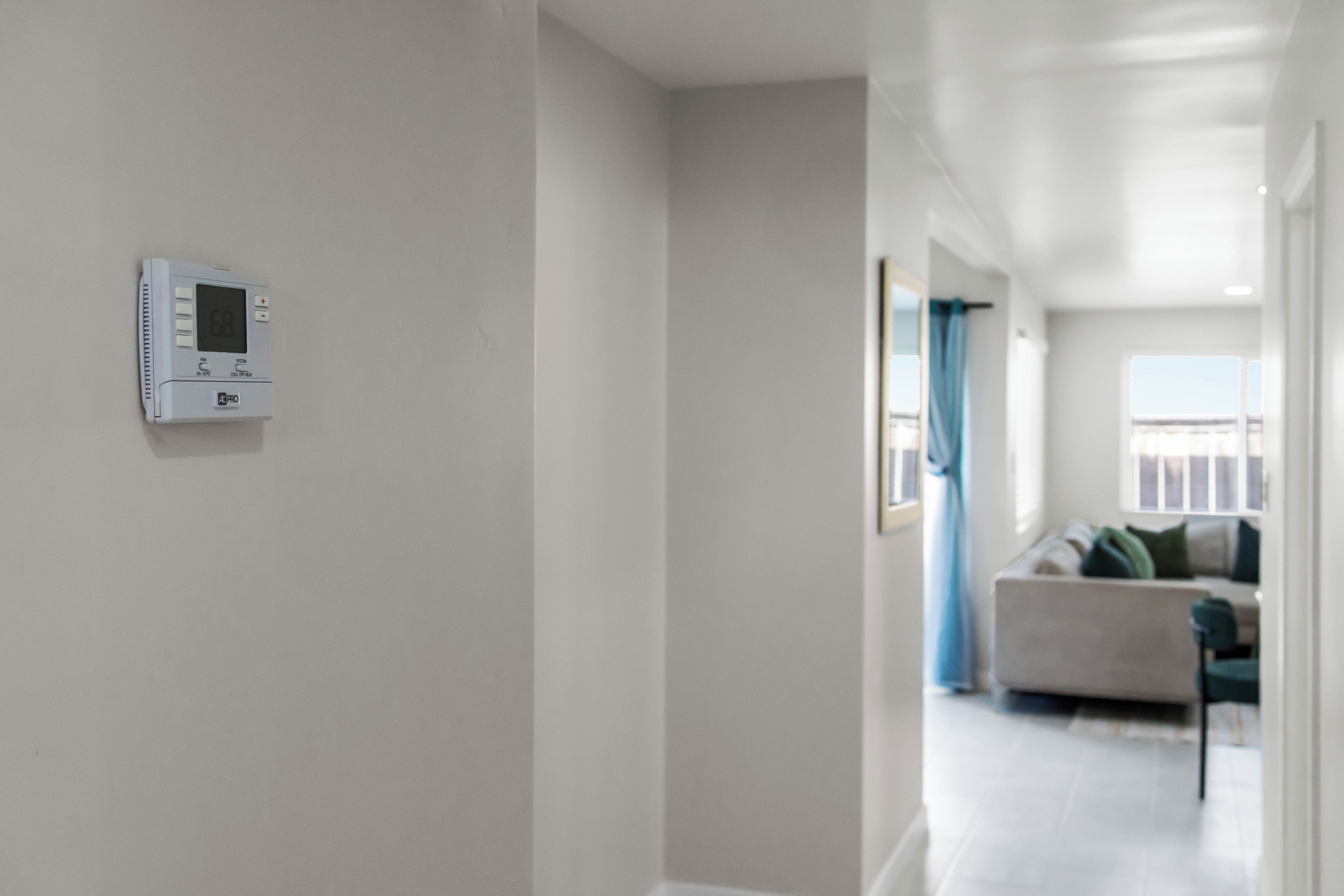 A modern interior with a thermostat on the wall, a sofa, and a view of the outdoors.