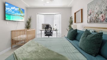 Une chambre à coucher avec un lit, un bureau et une chaise, une télévision et un tableau.