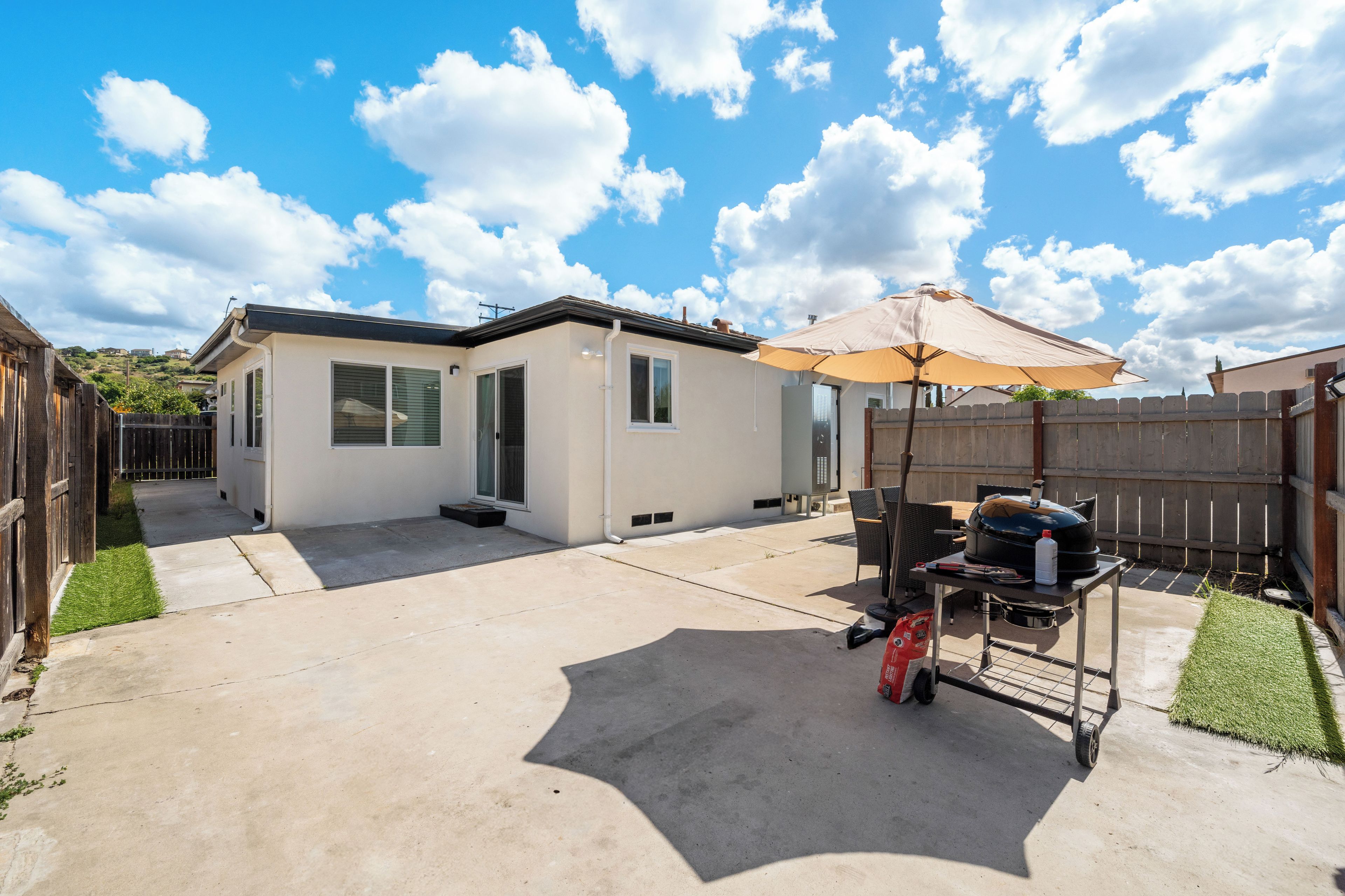 A residential backyard with a patio, a barbecue grill, and a covered seating area.