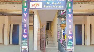 L'ingresso di un hotel con un cartello che indica camere vista città, disponibilità 24 ore su 24 e opzioni con o senza aria condizionata.