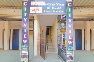 Entrada de hotel con un letrero que indica habitaciones con vista a la ciudad, disponibilidad las 24 horas y opciones con o sin aire acondicionado.
