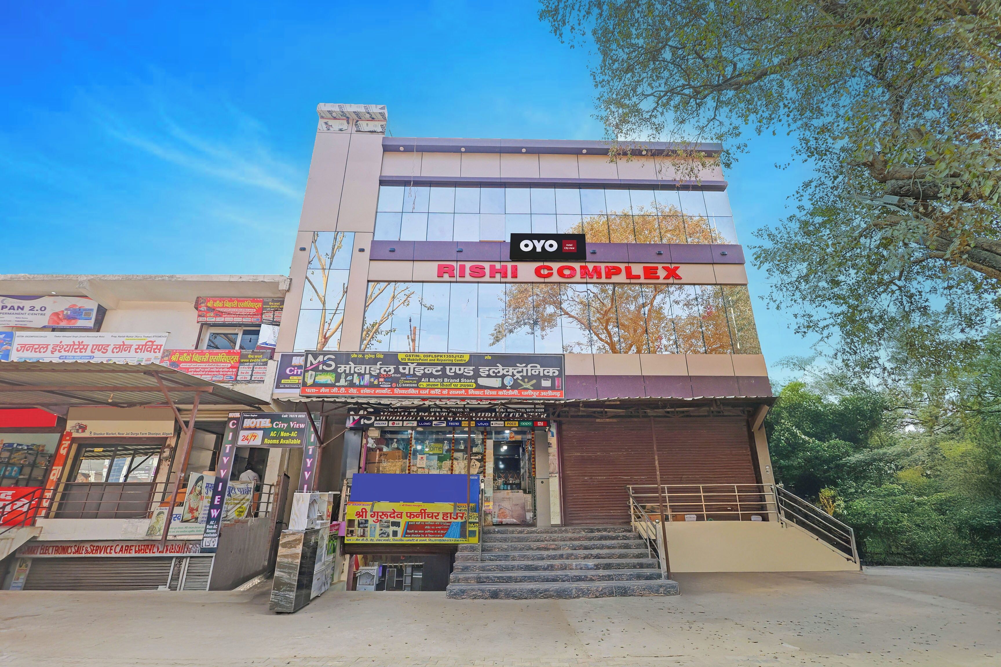 A hotel complex with multiple shops on the ground floor, including a mobile phone and electronics store.
