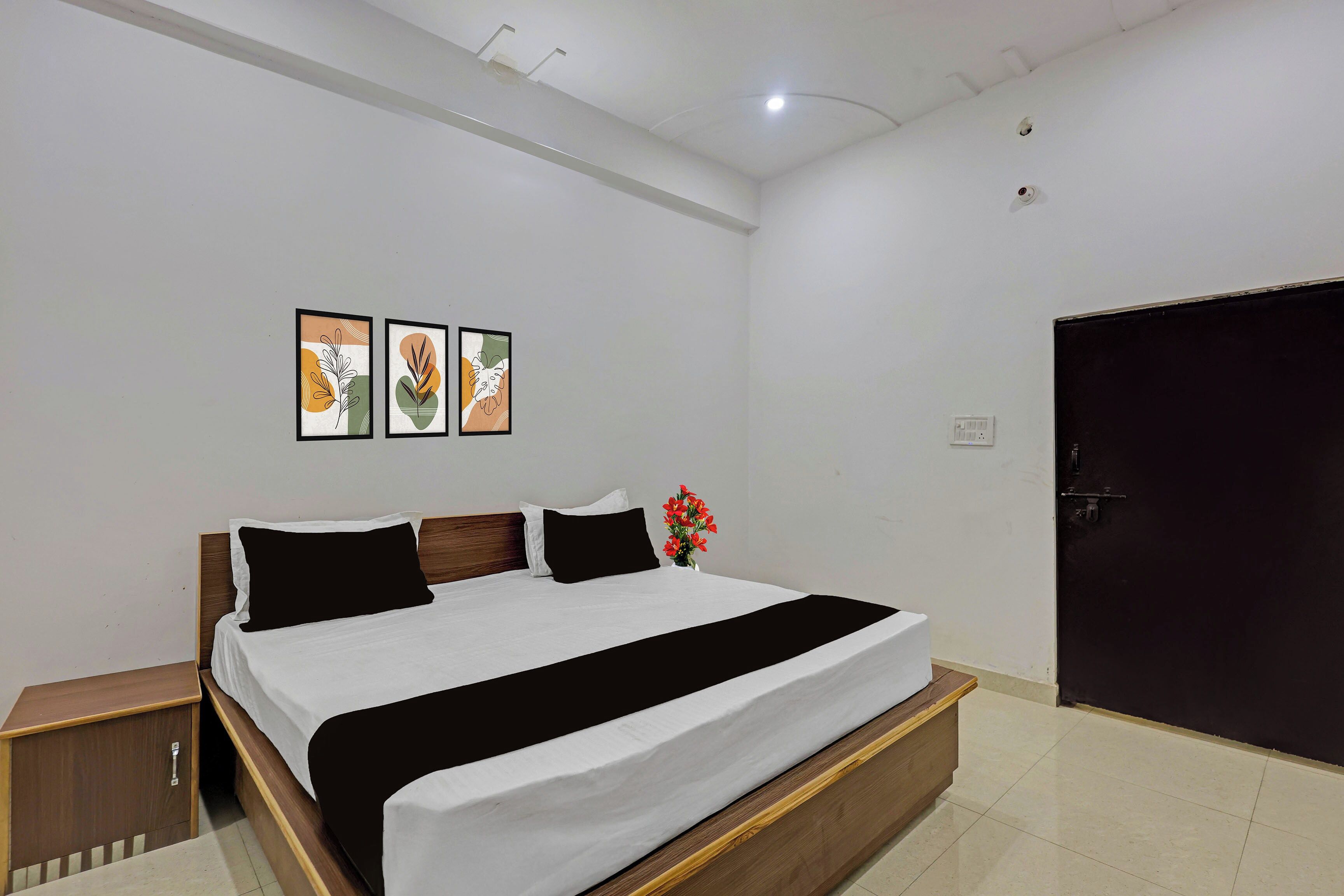 Un dormitorio con cama, mesita de noche, lámpara de pared y una puerta.