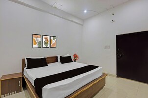 A bedroom with a bed, a nightstand, a wall-mounted light, and a door.