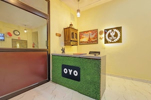 A reception desk with a green artificial grass accent, a clock, and a framed picture of the Eiffel Tower.