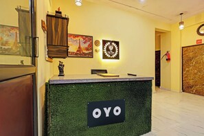 Uma receção com uma placa a indicar 'OYO' no saguão de um hotel.