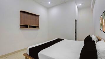 A bedroom with a single bed, a wooden shelf, a door, and a wall-mounted artwork.