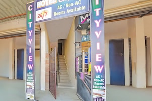 A hotel entrance with a sign indicating 24/7 room availability and a staircase leading to the rooms.