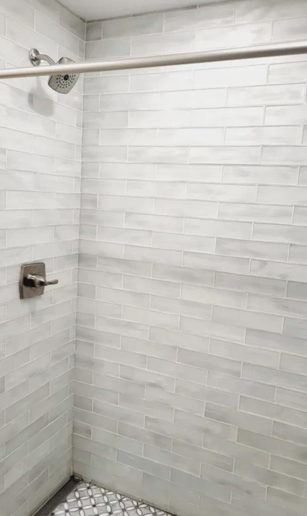 A shower area with white subway tiles and a metal showerhead.