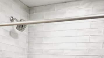 A shower area with white subway tiles and a metal showerhead.