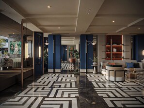 A modern hotel lobby with a geometric patterned floor, a seating area with a sofa and armchairs, and a bookshelf with books and decorative items. - Hôtel Étoilée Hanoï (Cau Giay)