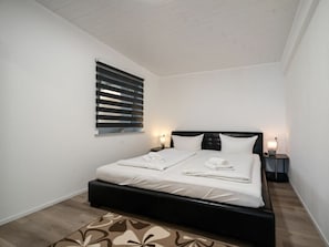 Ein Einzelbett mit schwarzem Kopfteil, weißer Bettwäsche und einem gemusterten Teppich.