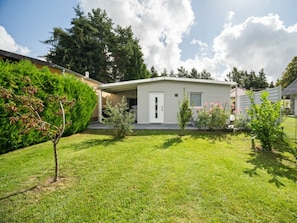 Ein Bungalow mit einer Haustür, einer kleinen Veranda und einem gepflegten Rasen.