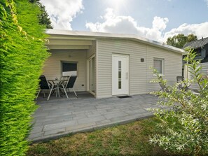 Ein Bungalow mit Terrasse, einer Tür und einem Fenster.