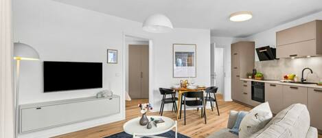 A modern living room with a sofa, a dining table, and a TV mounted on the wall.