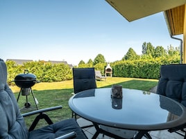 Un patio exterior con una mesa redonda y dos sillas, una parrilla y un horno de pizza.