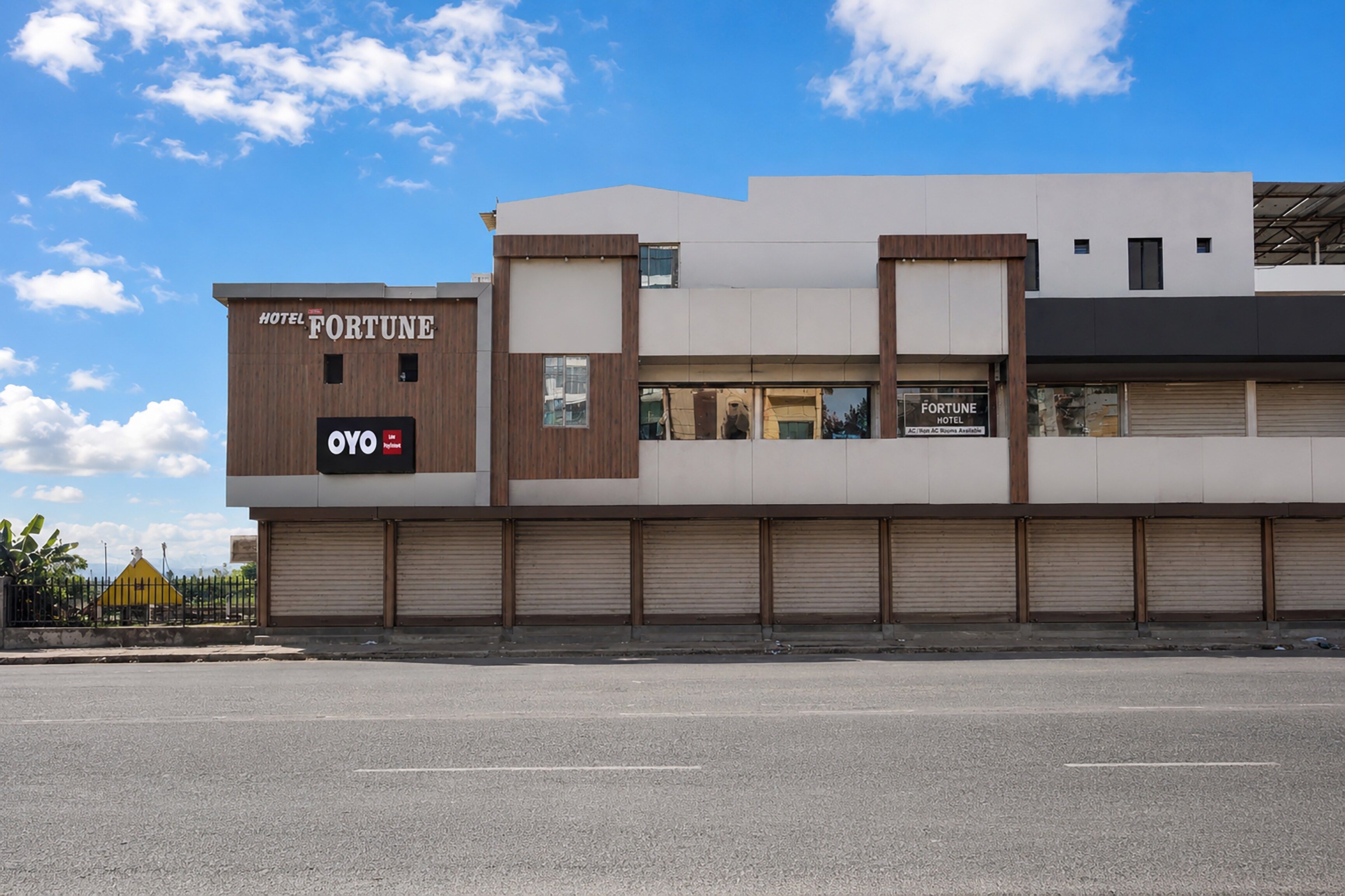 A modern hotel building with a sign for the Fortune Hotel and a visible OYO logo.