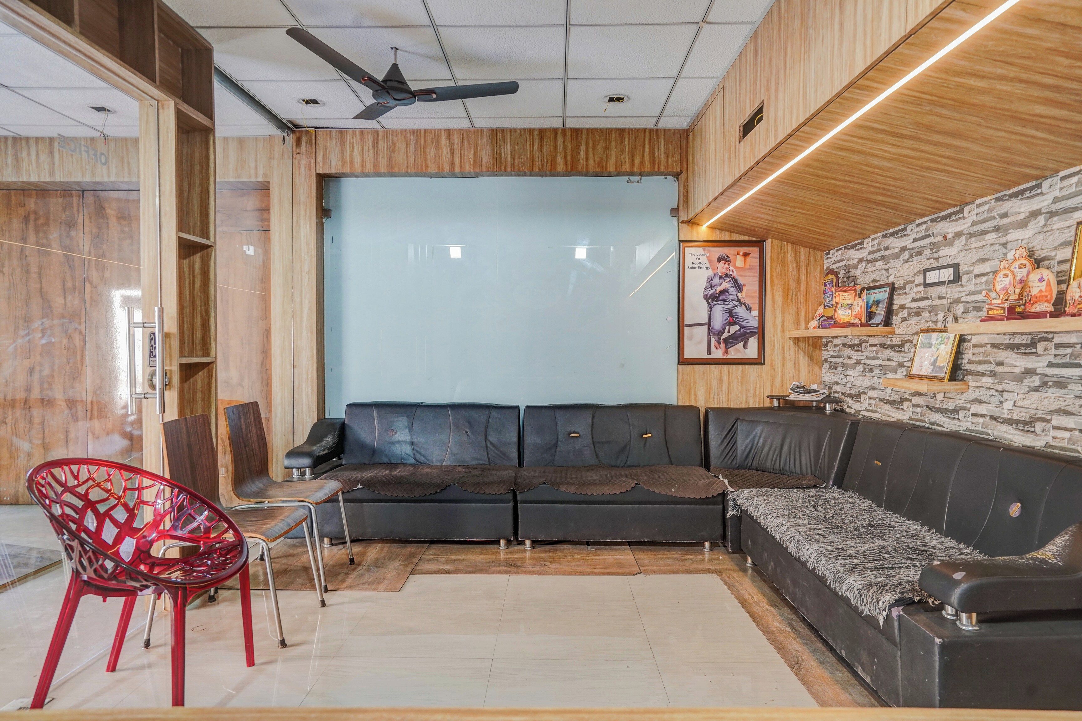 A modern interior with a sectional sofa, a red chair, and a ceiling fan.