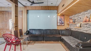 A modern interior with a sectional sofa, a red chair, and a ceiling fan.