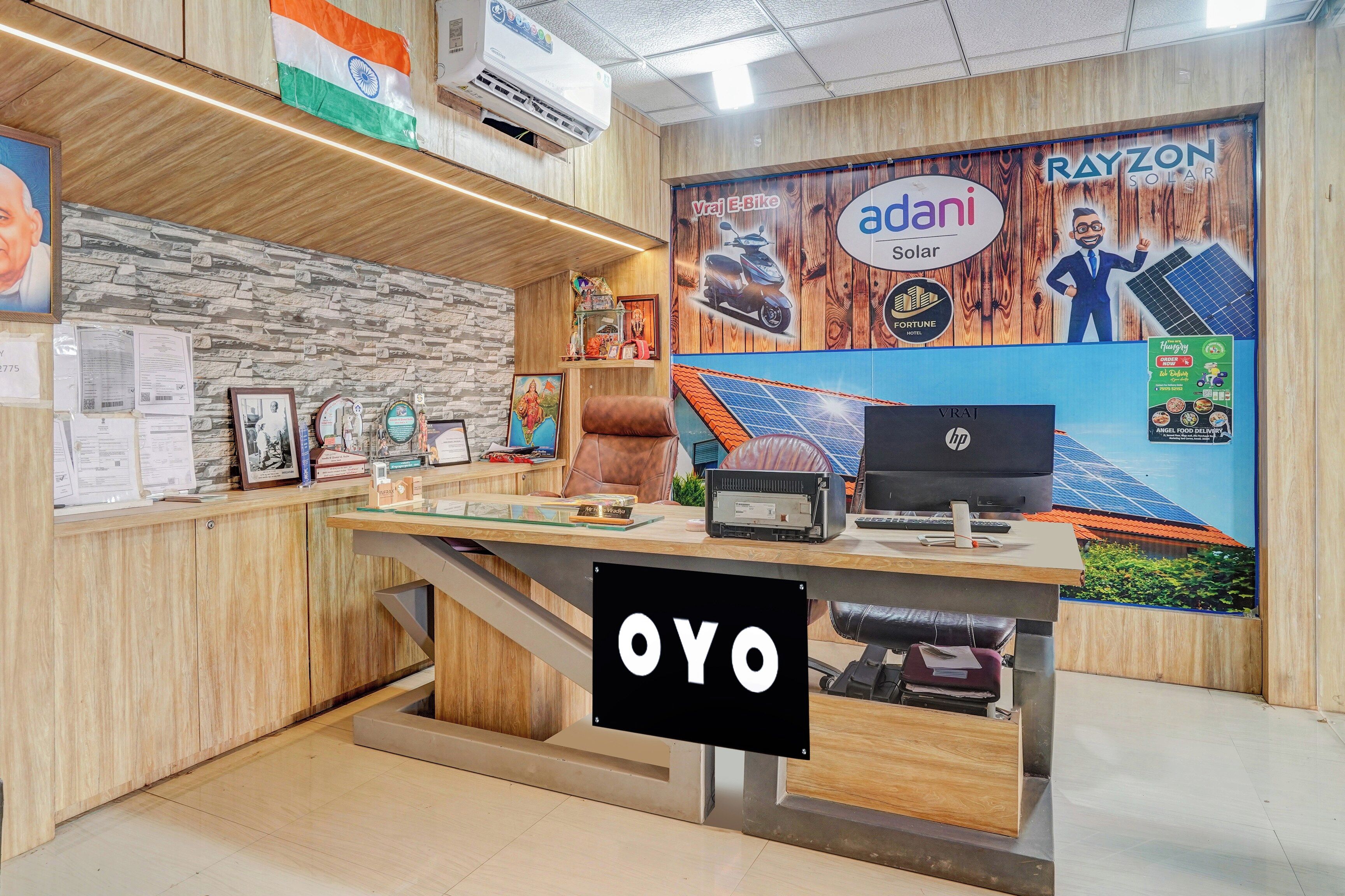 A reception desk with a wooden finish, a mounted Indian flag, and a Rayzon Solar advertisement.