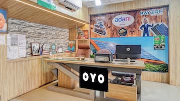 A reception desk with a wooden finish, a mounted Indian flag, and a Rayzon Solar advertisement.