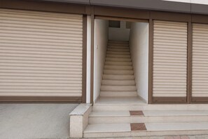 A staircase leading to an upper floor with closed roller shutters on either side.