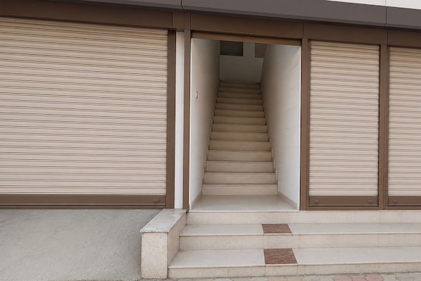 Un escalier menant à l’étage supérieur, avec des volets roulants fermés de chaque côté.
