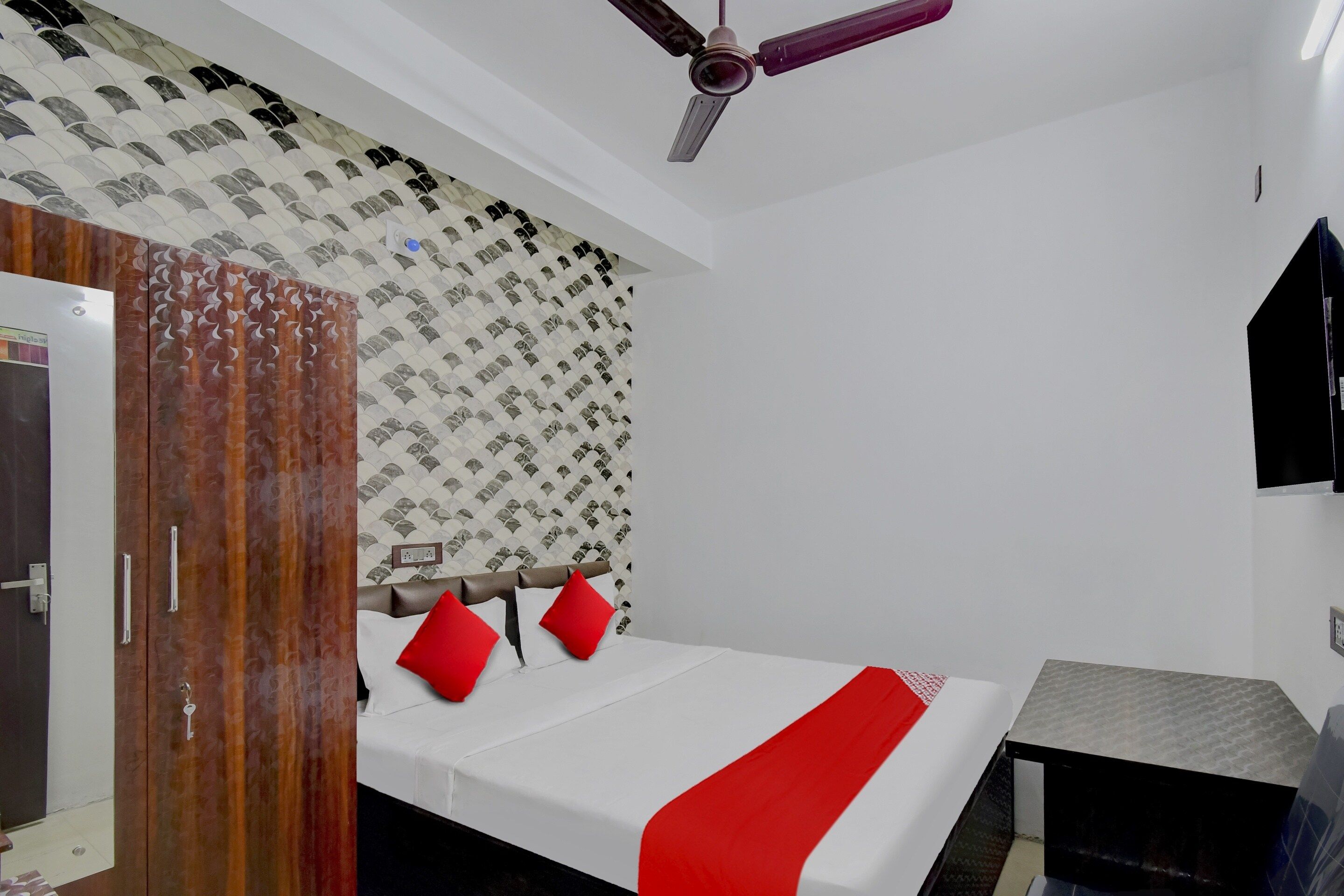 Une chambre à coucher avec un lit, une armoire, un ventilateur de plafond et un mur décoré de motifs.