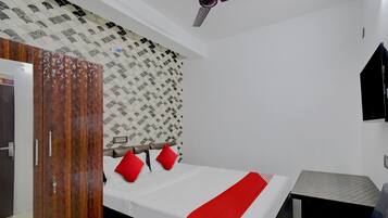 Une chambre à coucher avec un lit, une armoire, un ventilateur de plafond et un mur décoré de motifs.