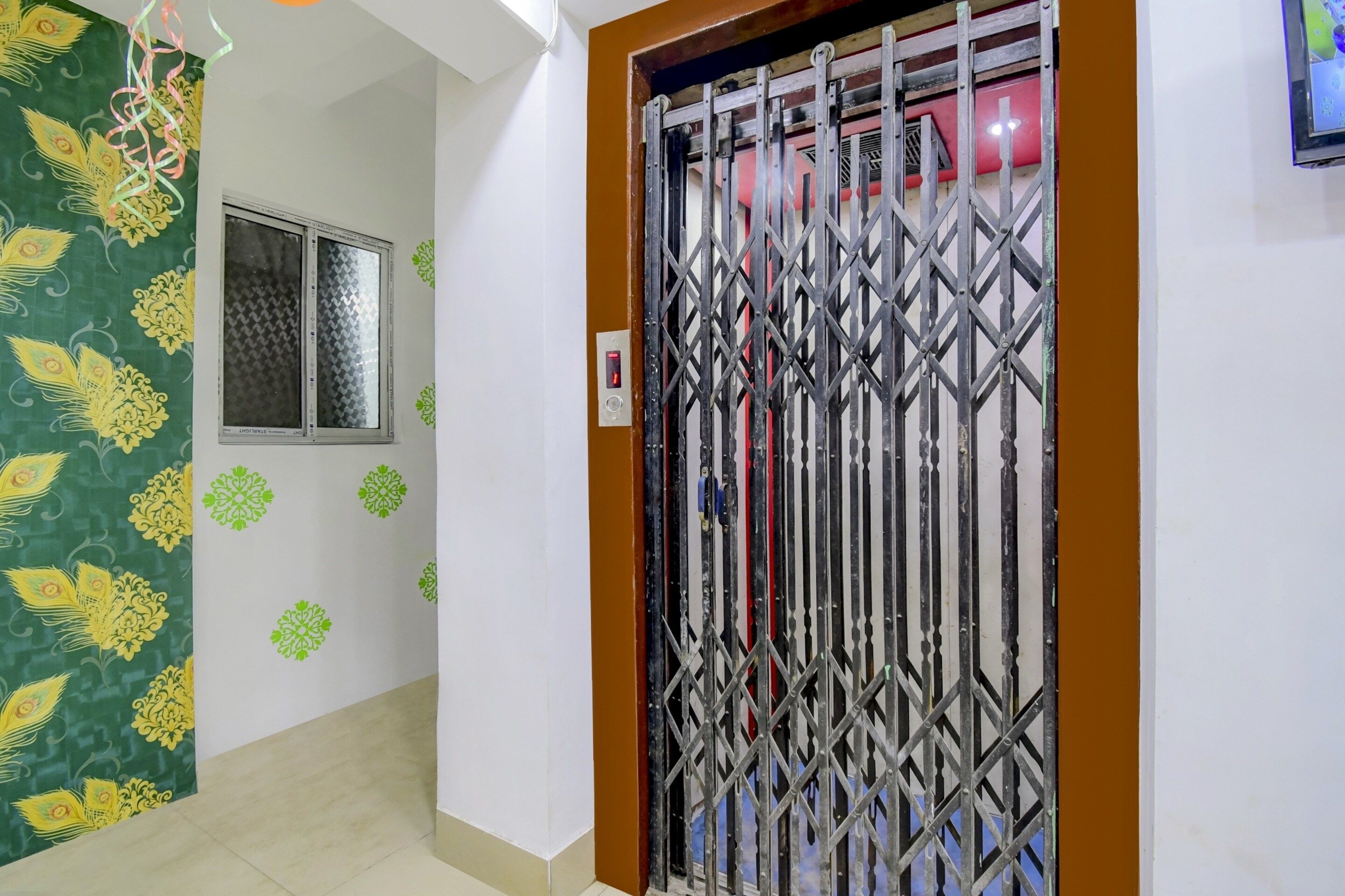 A hallway with a decorative green wall, a window, and a metal gate.