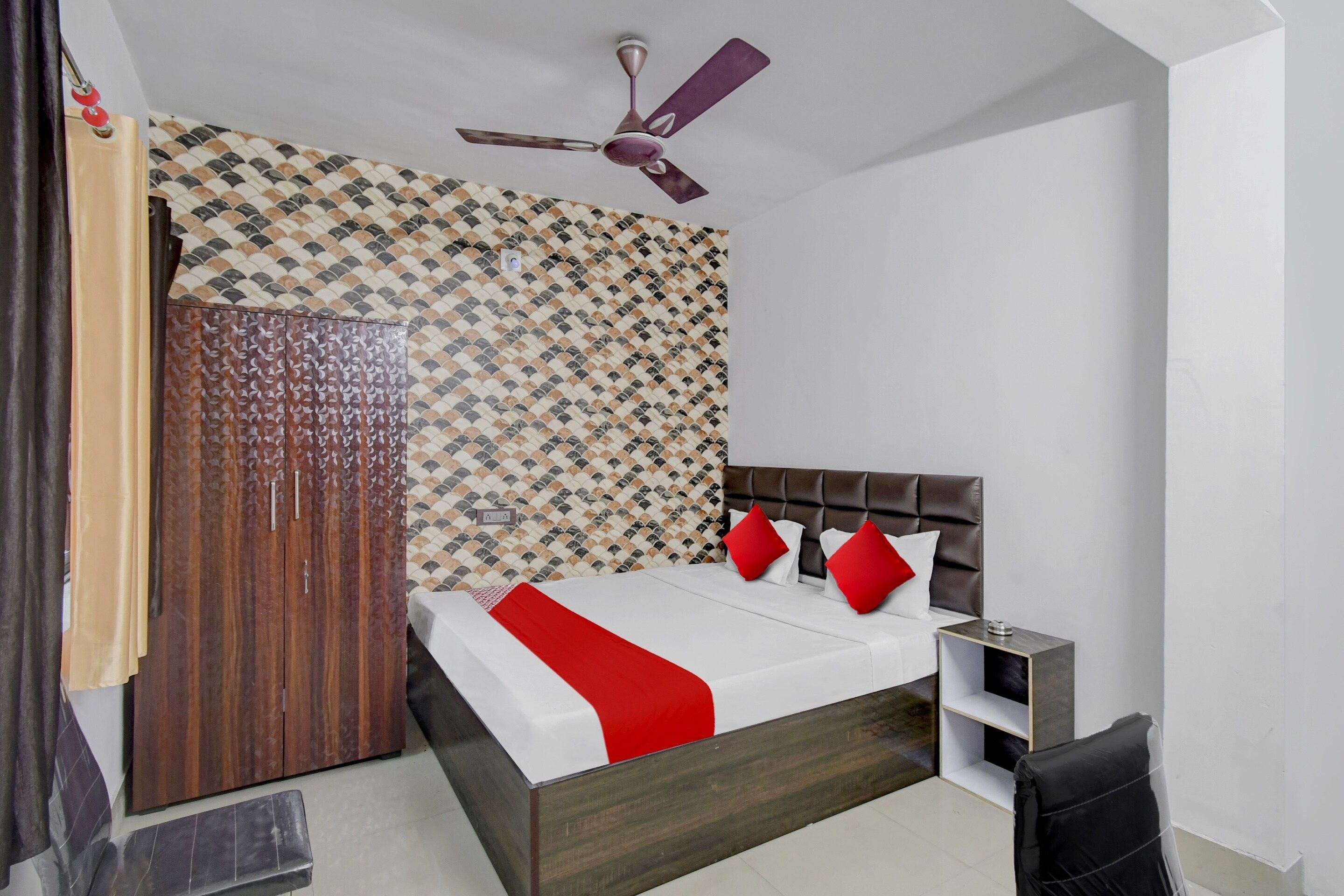 Quarto com cama, guarda-roupa, ventoinha no teto e parede estampada.
