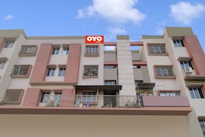Un edificio de varios pisos con un letrero que dice 'OYO ROOMS', indicando un hotel o alojamiento.