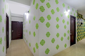 A hallway with patterned wallpaper, a tiled floor, and doors leading to different rooms. - Hotel O ALISHA LODGE (Asansol)