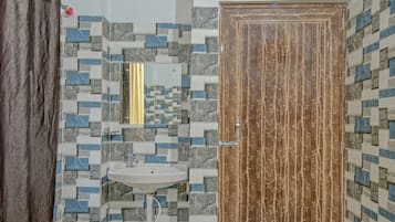 Un baño con pared de azulejos, un lavamanos y una puerta de madera.