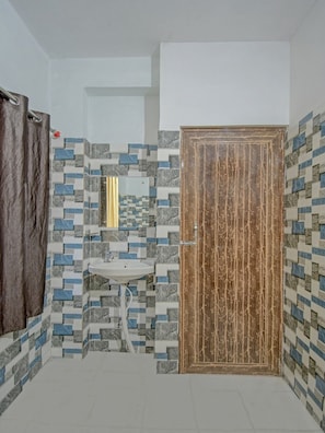 A bathroom with a tiled wall, a sink, and a wooden door.