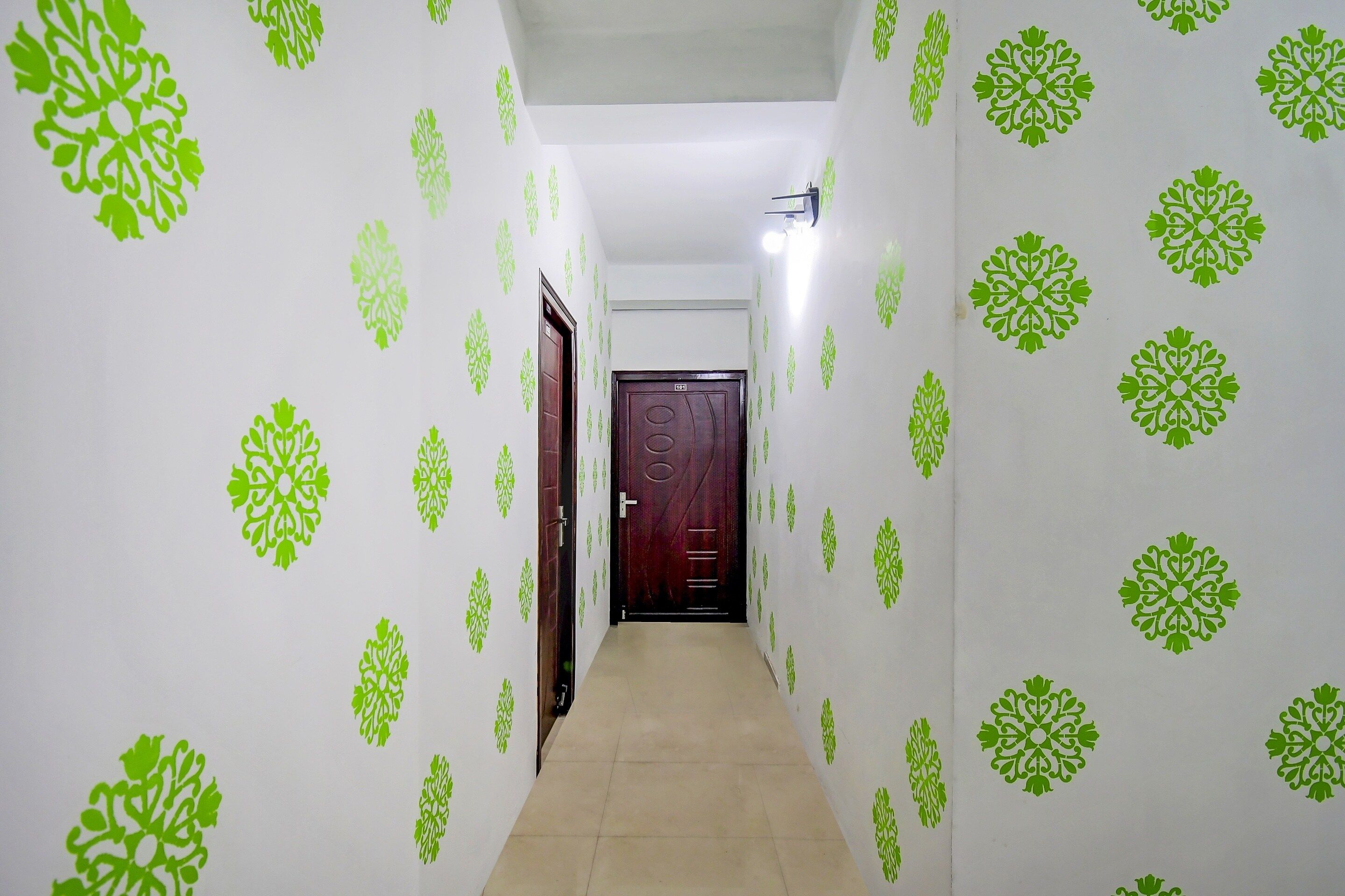 Um corredor com papel de parede estampado e uma porta no final.