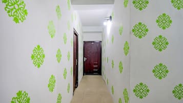Um corredor com papel de parede estampado e uma porta no final.